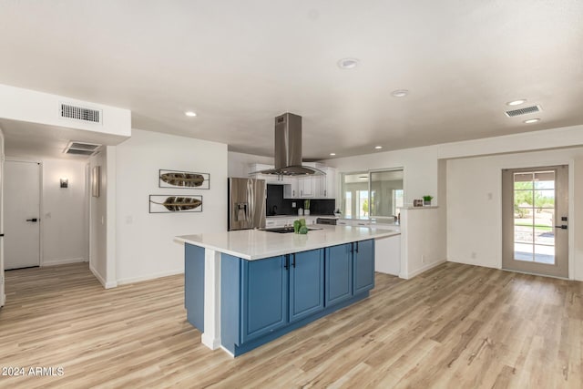 kitchen with island exhaust hood, stainless steel refrigerator with ice dispenser, blue cabinetry, a center island, and light hardwood / wood-style floors