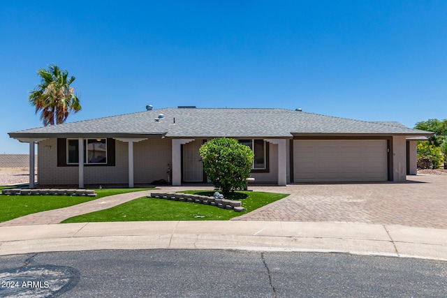 ranch-style house featuring a garage and a front lawn