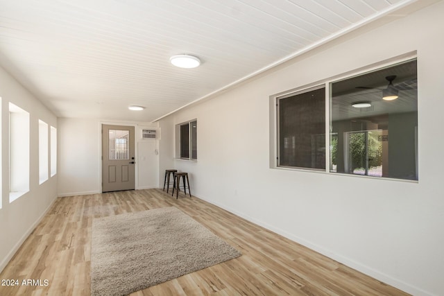 interior space with hardwood / wood-style floors, ceiling fan, and a wall unit AC