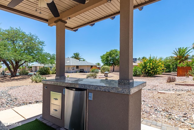 view of patio / terrace with area for grilling, ceiling fan, and a bar