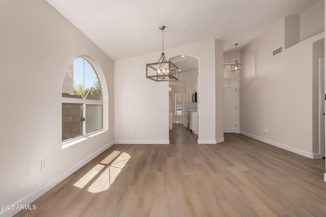 4526 E Bannock St, Phoenix, AZ 85044 - unfurnished dining area with wood finished floors, baseboards, arched walkways, and a chandelier