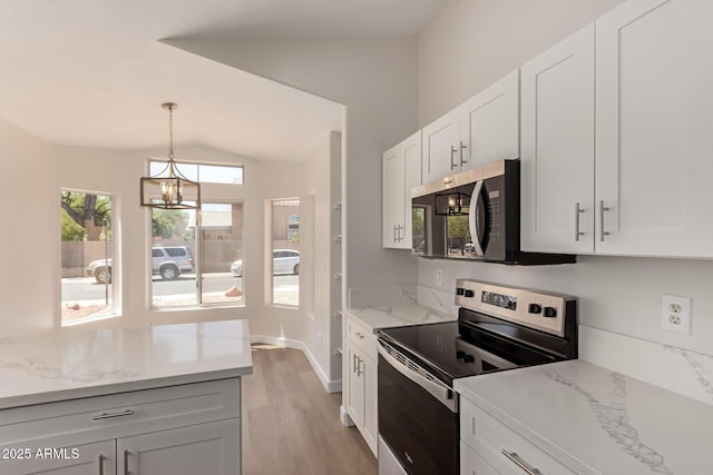 4526 E Bannock St, Phoenix, AZ 85044 - kitchen with appliances with stainless steel finishes, lofted ceiling, light wood-style floors, white cabinetry, and decorative light fixtures