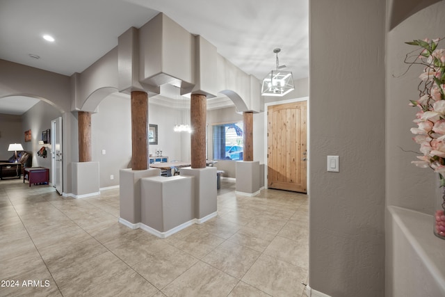 kitchen featuring pendant lighting, decorative columns, a chandelier, and light tile patterned floors