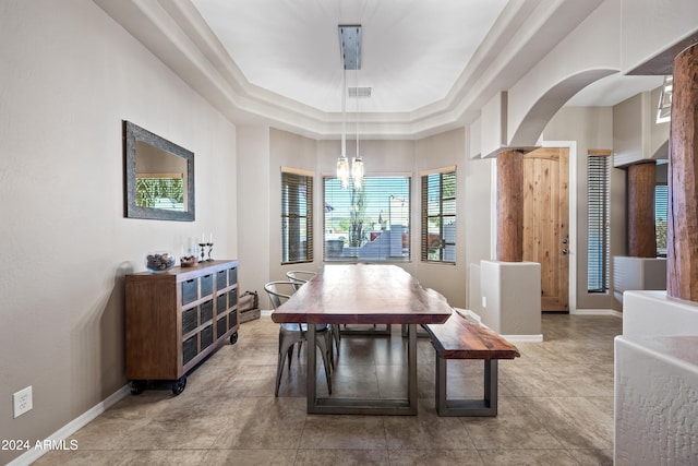 dining space featuring decorative columns, an inviting chandelier, and a tray ceiling