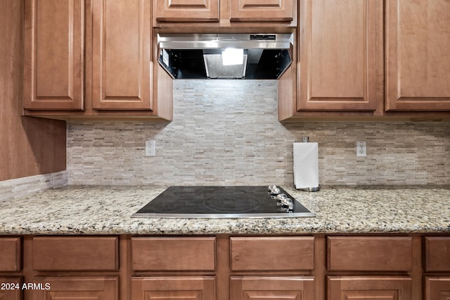 kitchen featuring ventilation hood, light stone counters, black electric cooktop, and backsplash