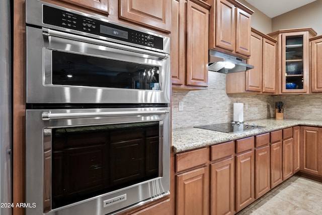 kitchen with tasteful backsplash, black electric cooktop, double oven, and light tile patterned floors