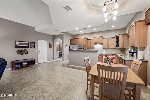 dining room with an inviting chandelier, sink, light tile patterned floors, and a raised ceiling