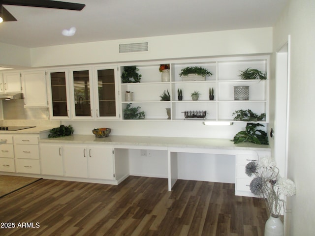 kitchen with dark hardwood / wood-style flooring, black electric stovetop, built in desk, and white cabinets