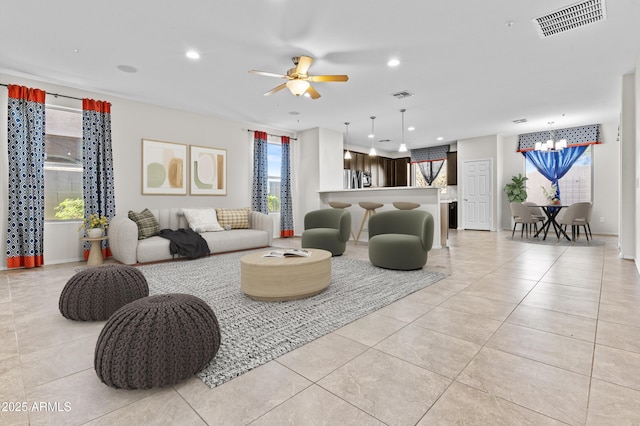 tiled living room featuring ceiling fan with notable chandelier