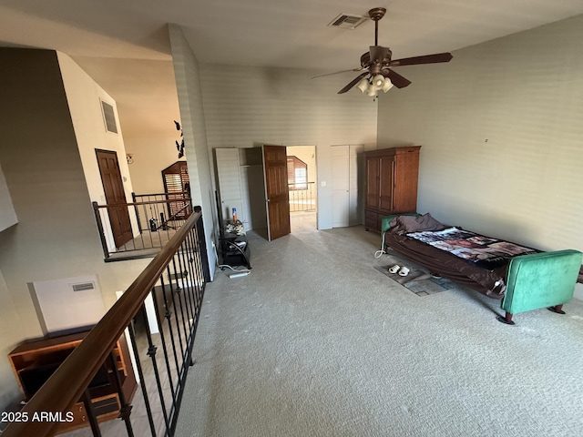 interior space featuring carpet, a high ceiling, visible vents, and an upstairs landing