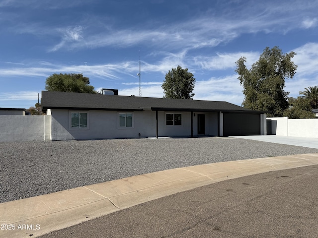 ranch-style house with a garage, driveway, stucco siding, and fence