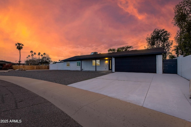 view of front of property with concrete driveway, a garage, and fence