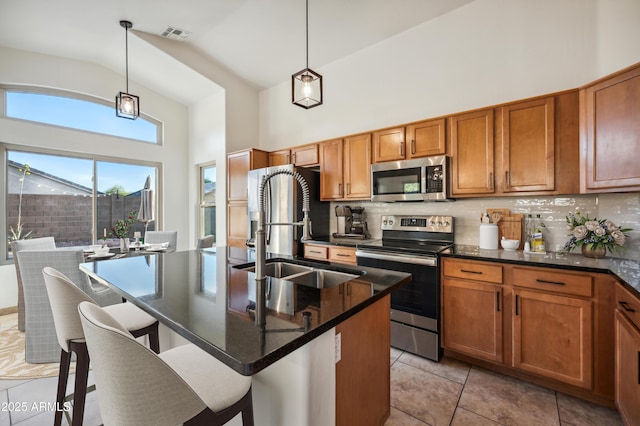 6309 W Hughes Dr, Phoenix, AZ 85043 - kitchen with stainless steel appliances, a sink, brown cabinets, high vaulted ceiling, and a kitchen bar