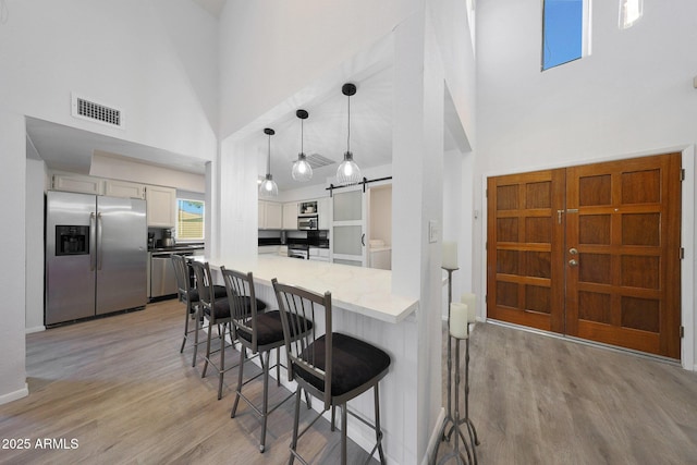 kitchen with appliances with stainless steel finishes, white cabinetry, a breakfast bar area, kitchen peninsula, and a barn door