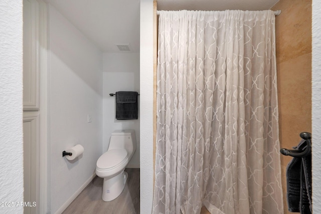 bathroom featuring hardwood / wood-style flooring, toilet, and walk in shower