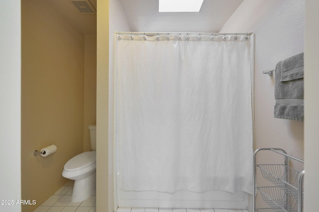 bathroom with tile patterned flooring, toilet, and a skylight