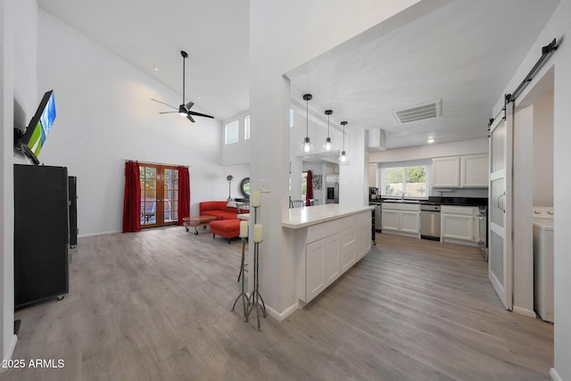 kitchen featuring a barn door, decorative light fixtures, light hardwood / wood-style floors, and white cabinets