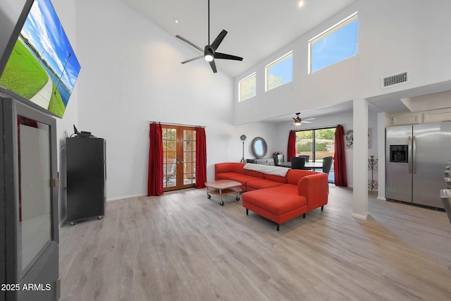 living room with french doors, ceiling fan, and light wood-type flooring