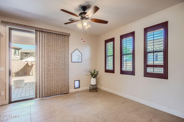 empty room with light tile patterned flooring, ceiling fan, and plenty of natural light