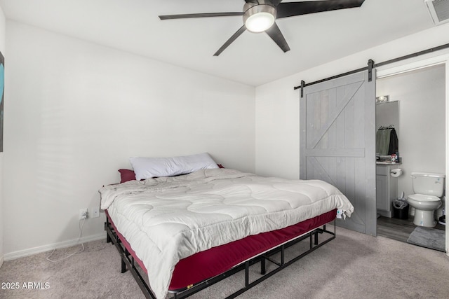 bedroom with ceiling fan, connected bathroom, light carpet, and a barn door