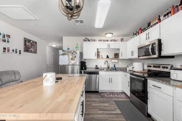 kitchen with white cabinets, dark wood-type flooring, butcher block counters, stainless steel appliances, and sink