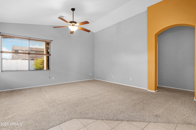 empty room with light tile patterned floors, a ceiling fan, lofted ceiling, arched walkways, and light carpet