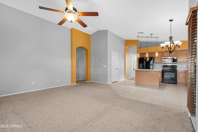 kitchen with arched walkways, black appliances, open floor plan, and light carpet