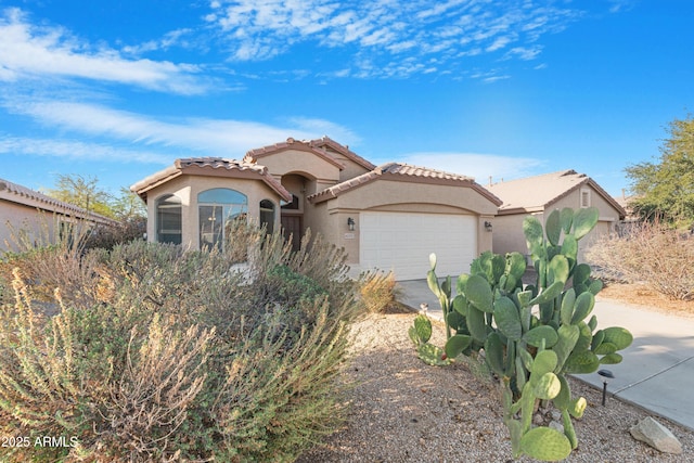 mediterranean / spanish-style house with a tile roof, a garage, driveway, and stucco siding