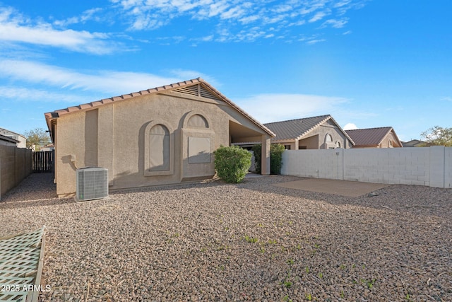 rear view of house with a fenced backyard, stucco siding, central air condition unit, a tiled roof, and a patio area