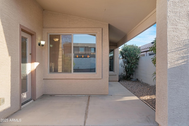 doorway to property featuring a patio area, stucco siding, and fence