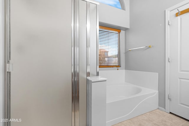 bathroom featuring tile patterned flooring, a garden tub, and a shower stall