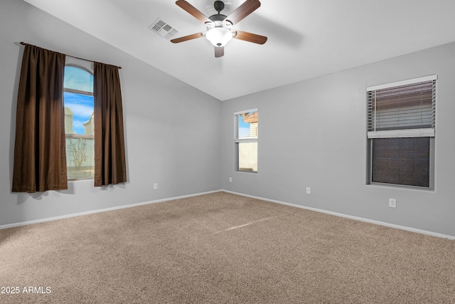 carpeted spare room with lofted ceiling, a ceiling fan, visible vents, and baseboards