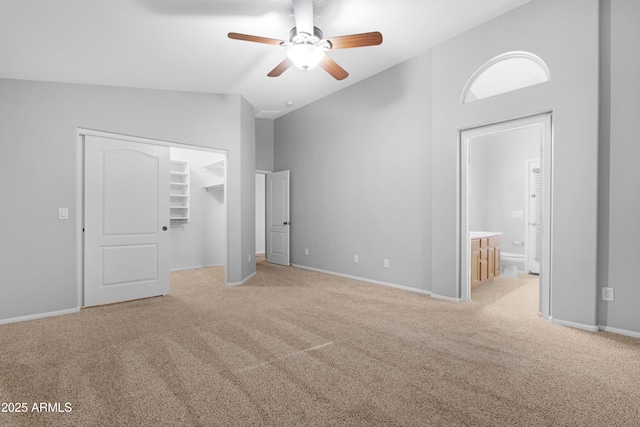 unfurnished bedroom featuring baseboards, a walk in closet, carpet, and vaulted ceiling