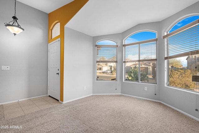 spare room with light tile patterned floors, baseboards, light colored carpet, and vaulted ceiling