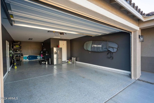 garage featuring stainless steel fridge and a garage door opener