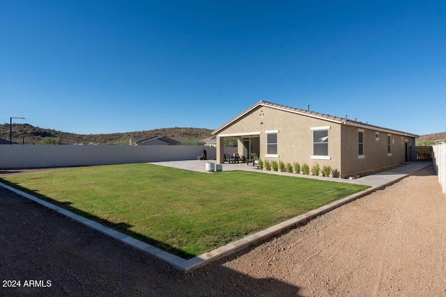 back of house with a lawn and a patio