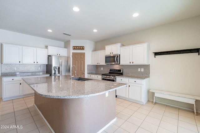 kitchen with a center island with sink, appliances with stainless steel finishes, sink, and white cabinetry