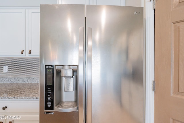 interior details featuring decorative backsplash, light stone countertops, white cabinets, and stainless steel refrigerator with ice dispenser