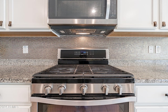 room details with light stone counters, white cabinetry, stainless steel appliances, and tasteful backsplash