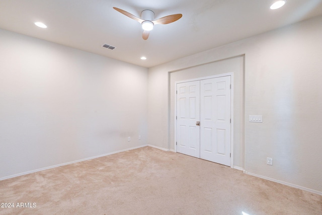 unfurnished bedroom featuring a closet, light carpet, and ceiling fan