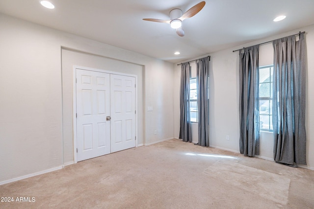 unfurnished bedroom with ceiling fan, a closet, and light carpet