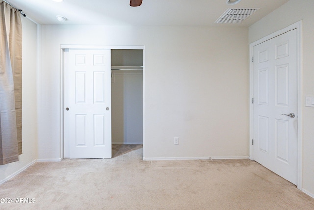 unfurnished bedroom with ceiling fan, light colored carpet, and a closet