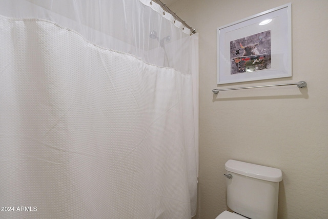 bathroom with toilet and a shower with curtain