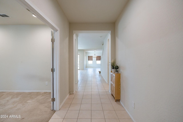 hall with a notable chandelier and light colored carpet