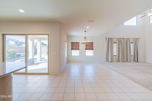 carpeted spare room featuring ceiling fan with notable chandelier