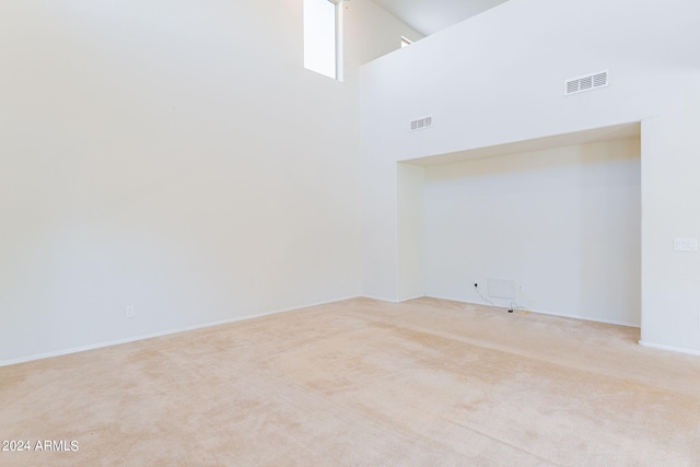 carpeted spare room featuring high vaulted ceiling