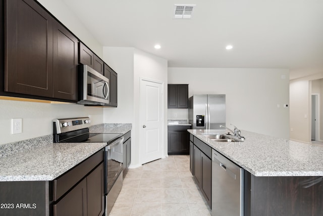 kitchen featuring light tile patterned flooring, sink, a kitchen island with sink, appliances with stainless steel finishes, and dark brown cabinets