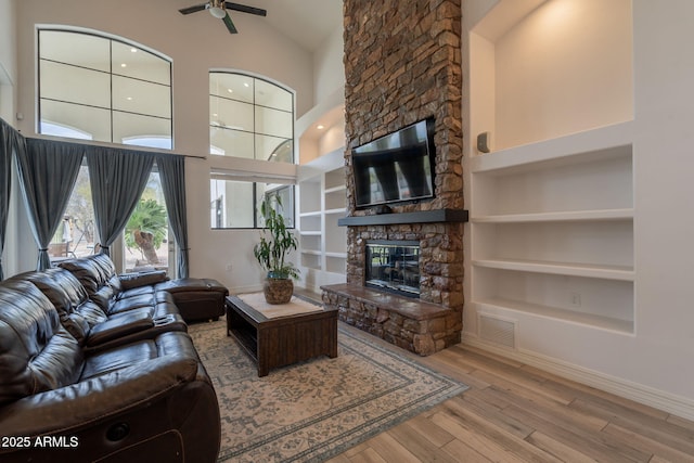 8502 E Santa Catalina Dr, Scottsdale, AZ 85255 - living room featuring ceiling fan, a stone fireplace, wood finished floors, built in shelves, and high vaulted ceiling