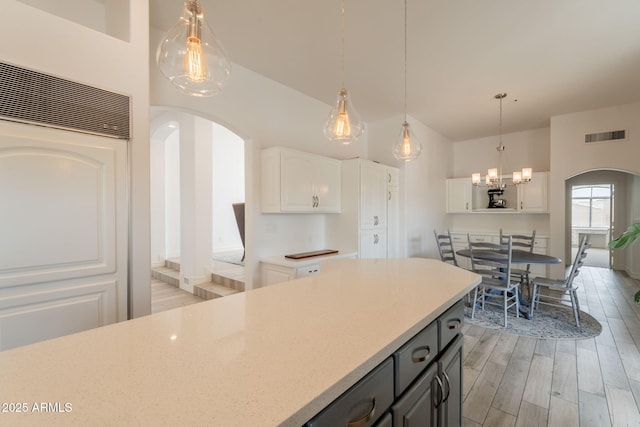 8502 E Santa Catalina Dr, Scottsdale, AZ 85255 - kitchen featuring arched walkways, light wood finished floors, white cabinets, and hanging light fixtures