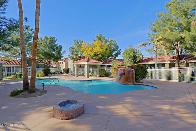 view of pool featuring a patio, an outdoor structure, pool water feature, and an outdoor fire pit